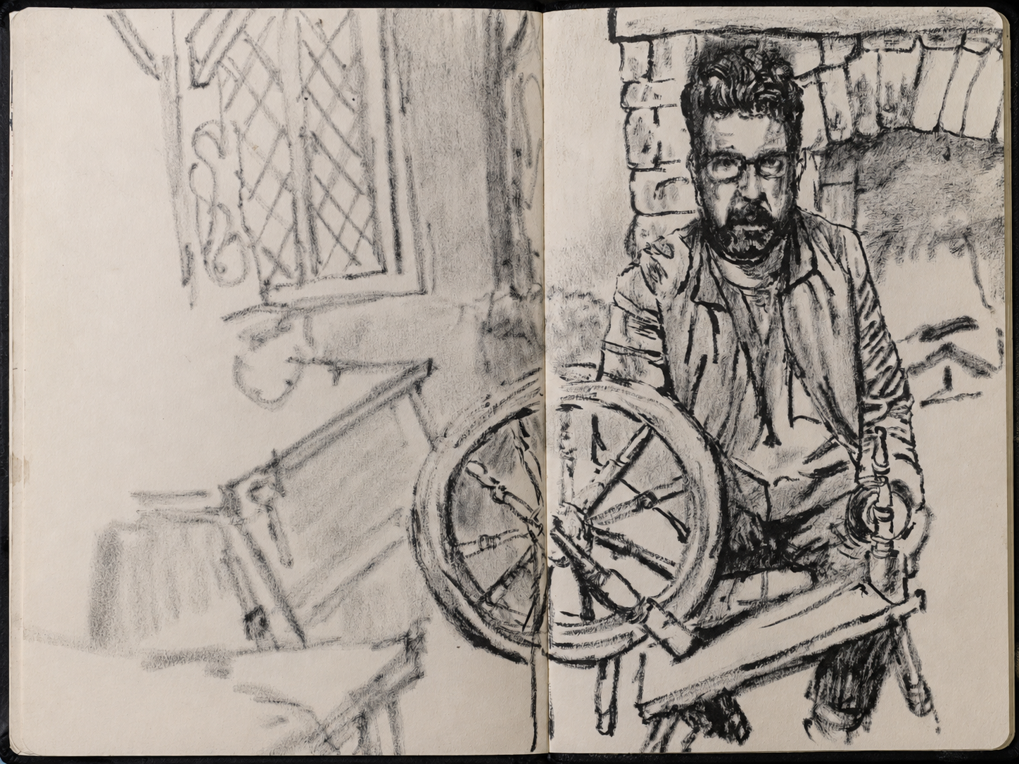 An open sketchbook spread: a softly drawn room and bicycle on the left, and a seated man holding a bicycle wheel on the right