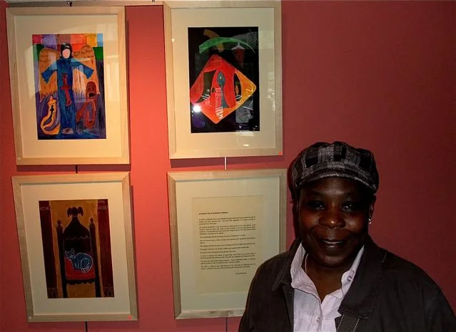 A visitor standing beside a group of colourful framed artworks