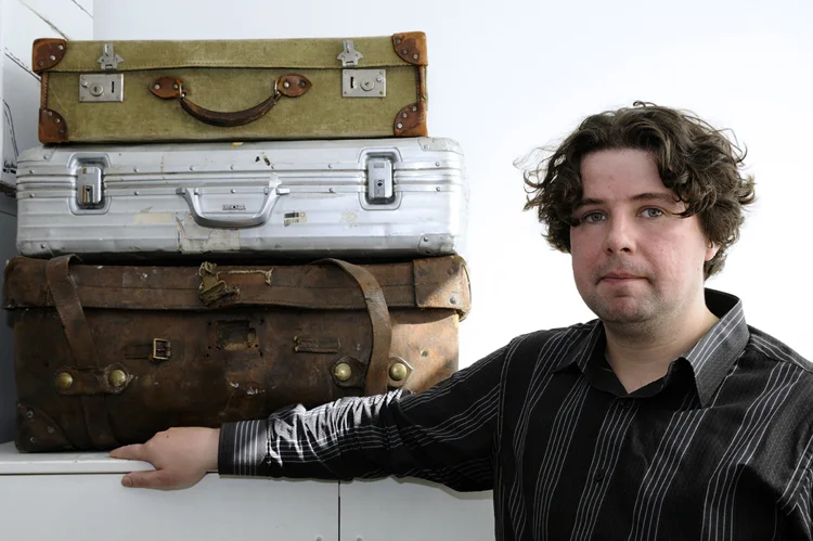 Jimmy Connelly beside a stack of old suitcases